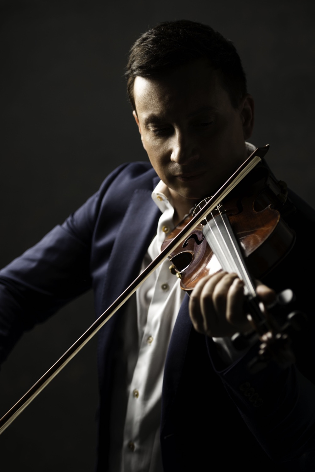 François Mathian playing the violin against a dark background